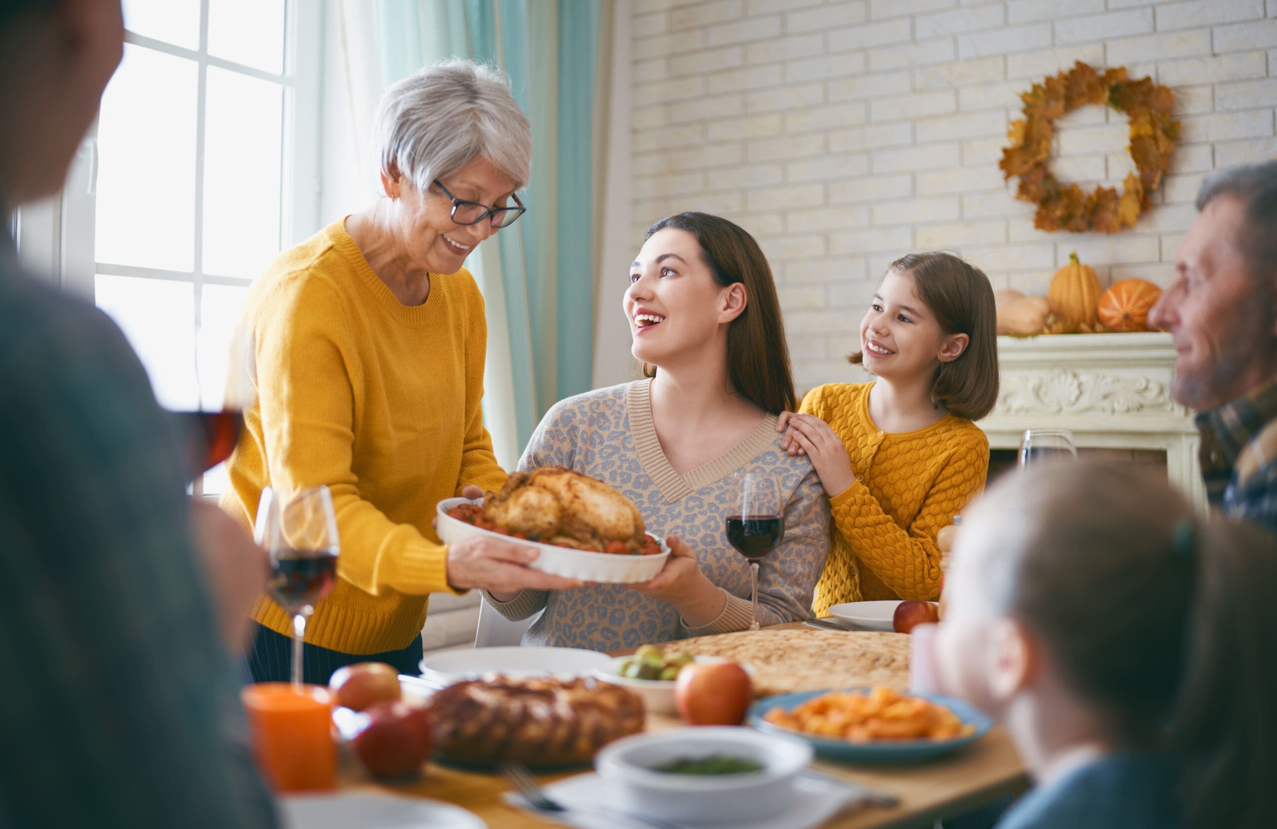 Multi-generational holiday dinner gathering. Autumn feast. Family sitting at the table and celebrating holiday. Grandparents, mother, father and children. Traditional dinner.